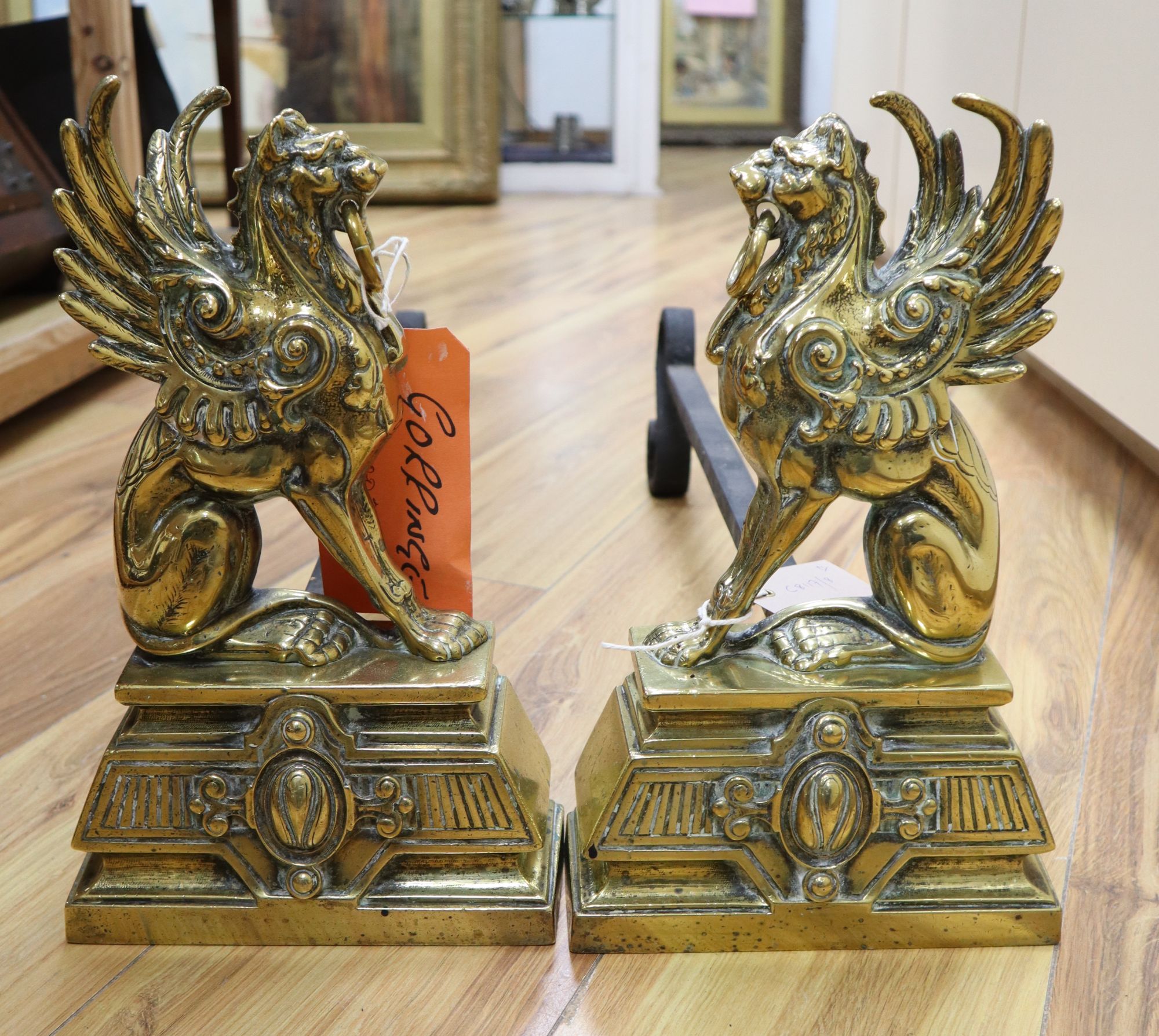 A pair of Victorian cast brass winged lion fire dogs, depth 53cm height 31cm